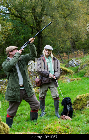 Il Galles del Nord, Snowdonia ; Gilar Farm. Un uomo e una donna fuori tiro con loro spaniel retriever. (MR) Foto Stock