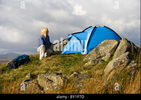Gilar Farm, Snowdonia, il Galles del Nord. Una donna per la configurazione del suo tenda mentre passeggiate in collina e campeggio selvaggio. (MR) Foto Stock
