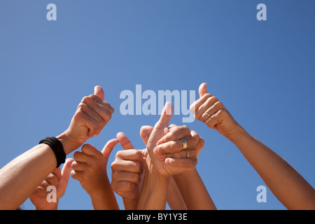 Molte le mani alzate verso il cielo blu (alcune sfocature) Foto Stock