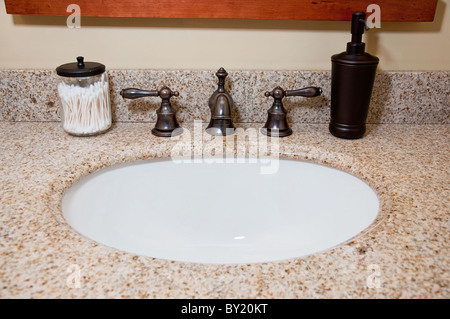 Il lavandino del bagno e il rubinetto con tamponi di cotone e dispensatore di sapone. Foto Stock