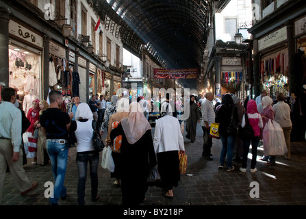 Gli acquirenti siriano a piedi attraverso la trafficata e affollata al mercato Hamidiyah, un tipico mezzo souq orientale nella città vecchia di Damasco, Siria. Foto Stock