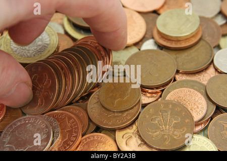 Dita di prelevare alcuni sterling 2p monete da una miscela di sterling monete Foto Stock