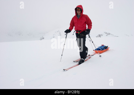 Glacier geologia dottorando sci attraverso il ghiacciaio di Brady durante whiteout condizioni di Blizzard, tirando una slitta di geofisiche Foto Stock