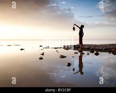 Un giovane ragazzo etiope tiene il suo pescato sulle rive del lago Langano, Etiopia. Foto Stock