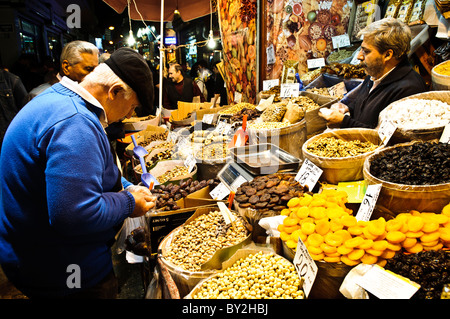 Bazar delle spezie frutta secca e cereali Istanbul Turchia // ISTANBUL, Turchia — i clienti acquistano cereali e frutta secca in un negozio adiacente al bazar delle spezie (noto anche come bazar egiziano o Mısır Çarşısı). Il Bazar delle spezie, costruito nel 1660 durante l'Impero Ottomano, è uno dei più antichi mercati coperti di Istanbul e un importante centro commerciale per spezie, delizie turche, frutta secca e noci. Situato nel quartiere di Eminönü vicino al Corno d'Oro, il bazar è stato originariamente costruito per generare entrate per il vicino complesso della nuova Moschea. Il mercato continua ad attirare sia la gente del posto che i turisti Foto Stock