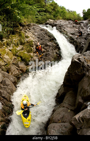 Vista aerea di un kayaker scendendo per una stretta e ripida rapida con altri kayakers guardando. Foto Stock