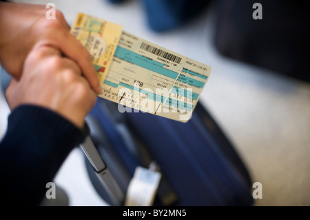 Una donna tiene su la sua carta di imbarco in attesa in linea in un aeroporto. Foto Stock