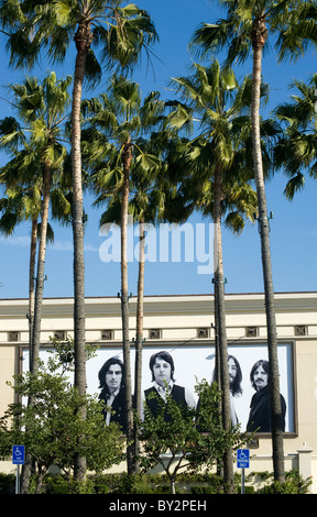 Il picco dei Beatles fuori da dietro palme sul loro cartellone per i tunes vicino al Mercato degli Agricoltori in Los Angeles Foto Stock