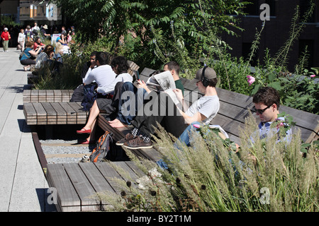 I giovani la lettura e il relax al sole, New York High Line parco pubblico, Manhattan. Foto Stock