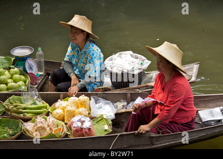 Due signore vendono frutta e altri prodotti alimentari nei tradizionali barche di legno su un canale laterale in 'Thai Cultural Village' Foto Stock