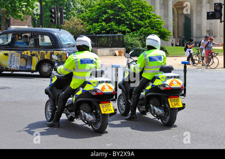 Due funzionari della Comunità di supporto della polizia Metropolitan che indossano caschi di crash cavalcando Piaggio MP3 tre scooter a ruote Hyde Park Corner London Inghilterra UK Foto Stock