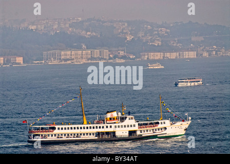 ISTANBUL, Turchia / Türkiye / Türkiye - un vecchio traghetto passeggeri sullo stretto del Bosforo nelle trafficate rotte di navigazione di Istanbul con la città di Istanbul sullo sfondo. Il Bosforo, una via d'acqua vitale che collega il Mar Nero al Mar di Marmara, offre splendide scene di Istanbul con i suoi monumenti storici e la vivace attività marittima. Questo iconico stretto divide la città in lati europei e asiatici, con splendidi palazzi sul lungomare, moschee e ponti. Foto Stock