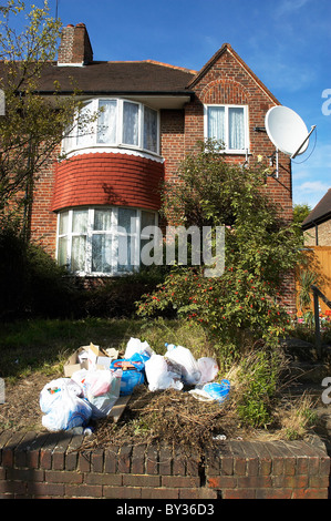 La spazzatura in giardino frontale di una casa suburbana. South London Regno Unito. Foto Stock