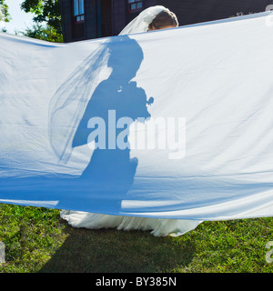 Silhouette di sposa dietro al foglio di grandi dimensioni in giardino Foto Stock