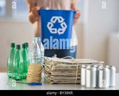 Donna di riciclaggio di bottiglie di plastica, lattine e quotidiani Foto Stock