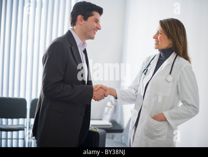 Stati Uniti d'America, New Jersey, Jersey City, medico rappresentante vendite stringono le mani con medico donna in office Foto Stock