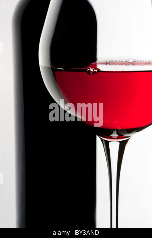 Still-life con bottiglia e bicchiere di vino rosso su sfondo bianco. Foto Stock