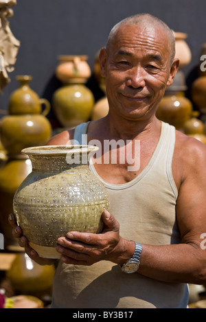 L'uomo vendita di ceramica in Menghai produrre mercato, nella provincia dello Yunnan, Regione di Xishuangbanna, Repubblica Popolare Cinese. JMH4199 Foto Stock