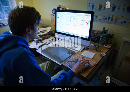 Studenti che lavorano nella sua camera da letto con un confuso scrivania e un imac. Foto Stock