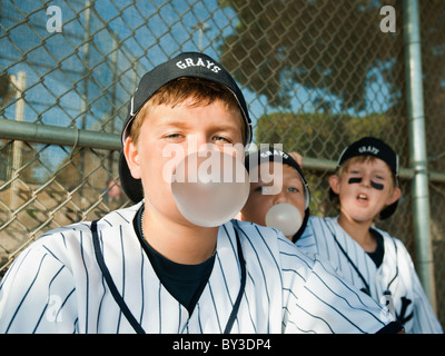 Stati Uniti, California, Ladera Ranch, ragazzi (10-11) da little League seduto sulla panchina e soffiando bubble gum Foto Stock