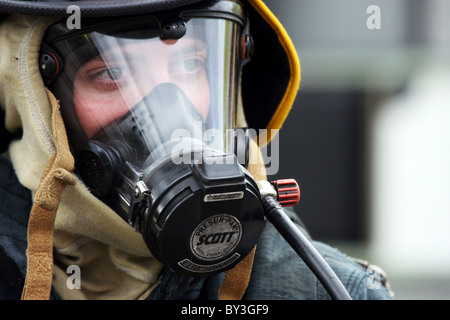 Un vigile del fuoco nella protezione ingranaggio di respirazione e maschera Foto Stock