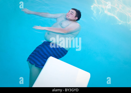 Hughson, California, Stati Uniti. Un adolescente obeso galleggia in una piscina. Foto Stock