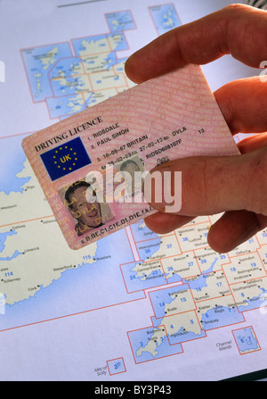 Il driver britannico di contenimento della patente di guida nella parte anteriore della mappa di viaggio Foto Stock
