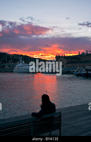Donna seduta su una panchina sulla Rambla de mar promeneade, Port Vell di Barcellona, Spagna Foto Stock