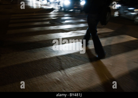 Persona che cammina sulle strisce pedonali notte street city town. Roma Italia Foto Stock