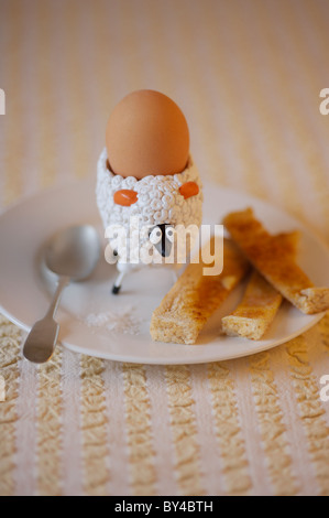Bambini uovo di pecora cup con uova sode e soldati imburrato Foto Stock