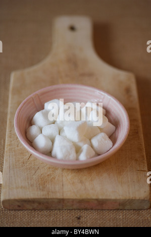 Zollette di zucchero in un recipiente su legno scheda servente Foto Stock