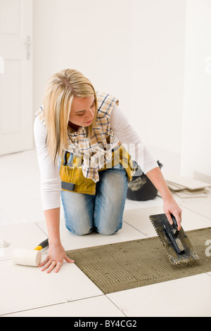 Home Improvement, ristrutturazione - handywoman posa di piastrelle, frattazzo con malta Foto Stock