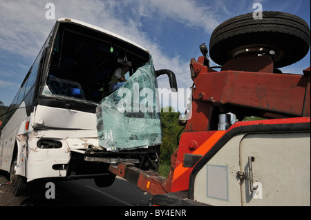 Distrutto con bus in frantumi il vetro del parabrezza dopo un incidente di macchina che viene tirata da un carrello di traino Foto Stock