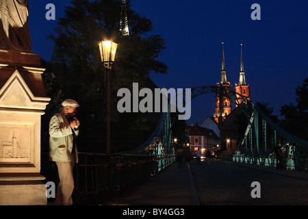 Busker suonare il flauto Tumski sul ponte, Cattedrale di San Giovanni Battista in background. Wroclaw, Bassa Slesia, Polonia. Foto Stock