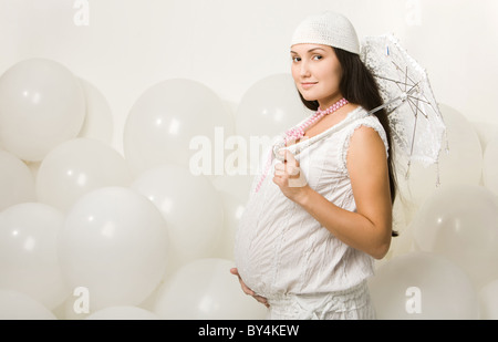 Ritratto di eleganti donna incinta in abiti alla moda azienda ombrello decorativi Foto Stock