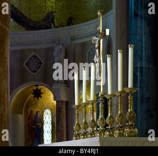 Set di ornati candelabri scolpito sull altare illuminato dalla luce solare con la più scura nicchie della chiesa dietro Foto Stock