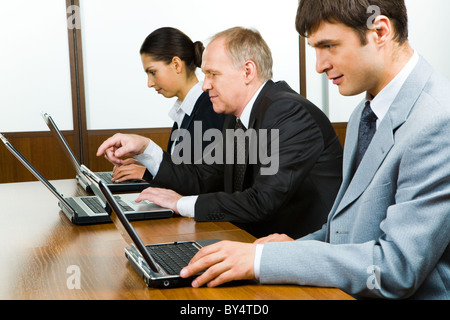 Fila di gente di affari di sedere a tavola e lavorare sui notebook Foto Stock