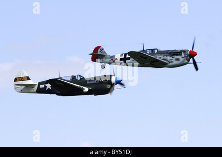Messerschmitt Bf 109G (CASA HA Buchon-1112) in Luftwaffe camouflage e Curtiss P-40N Warhawk in USAAF camouflage in formazione. Foto Stock