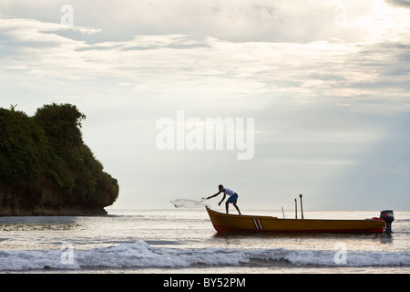 Fisherman casting net presso sunrise vicino Punta Cocles lungo la spiaggia incontaminata di Playa Cocles, Limon Provincia, Costa Rica. Foto Stock