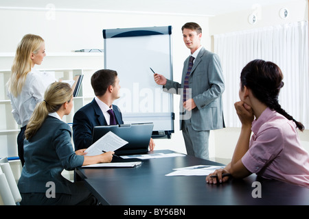 Immagine della Smart Business persone che guardano il loro leader mentre lui spiegare qualcosa su whiteboard durante il seminario Foto Stock