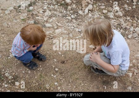 Due ragazzi guardando verso il basso in corrispondenza di un foro nella sporcizia Foto Stock