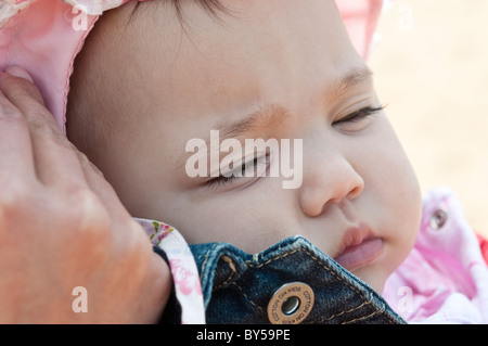 Il bambino dorme nella sua madre di braccia Foto Stock