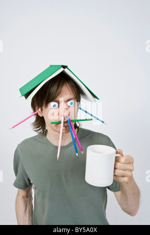 Strano uomo con matite, libro e caffè Foto Stock