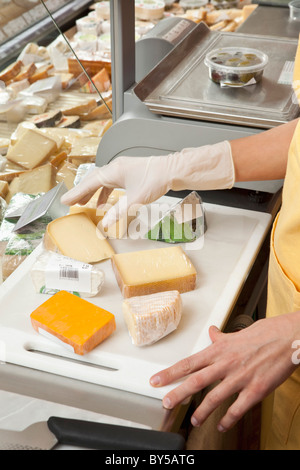 Un addetto alle vendite la preparazione di cunei di formaggio Foto Stock