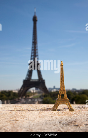 Una torre Eiffel souvenir replica accanto alla vera Torre Eiffel, la messa a fuoco su oggetti in primo piano Foto Stock