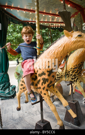 Un giovane ragazzo godendo di una corsa su una Merry Go Round. Foto Stock