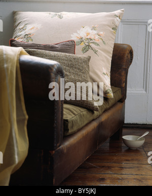 Close-up di tweed e cuscini floreali su marrone poltrona in pelle Foto Stock
