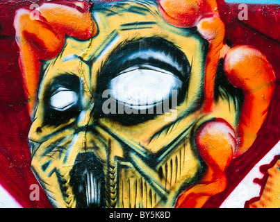 Graffiti che mostra un teschio giallo afferrata in una mano di grandi dimensioni Foto Stock