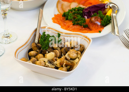 Piastra con aceto funghi sott'olio su tavola, posate per la cena, tovagliolo bianco, il fuoco selettivo. Foto Stock