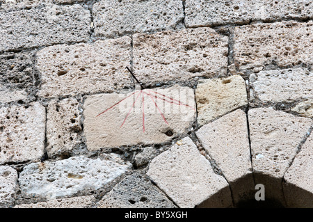 Una rudimentale scratch dial orologio sul muro della chiesa di St Genies de Fontedit, Francia, per mostrare le ore canoniche. Foto Stock